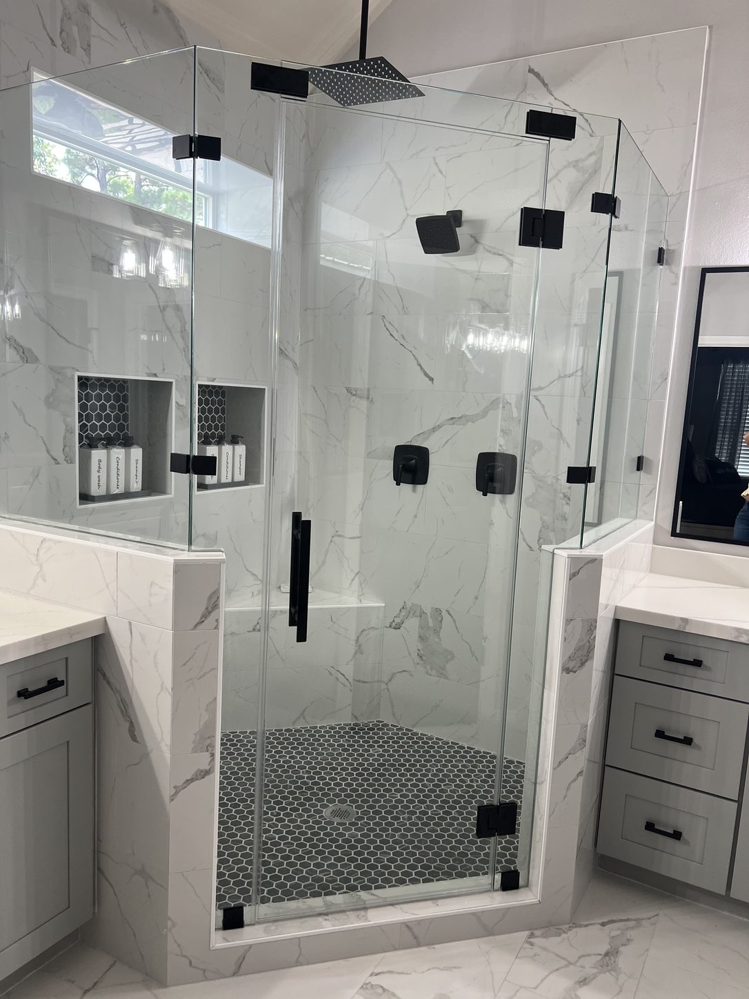Finished walk-in shower with clear glass, matte black hardware and a black mosaic floor