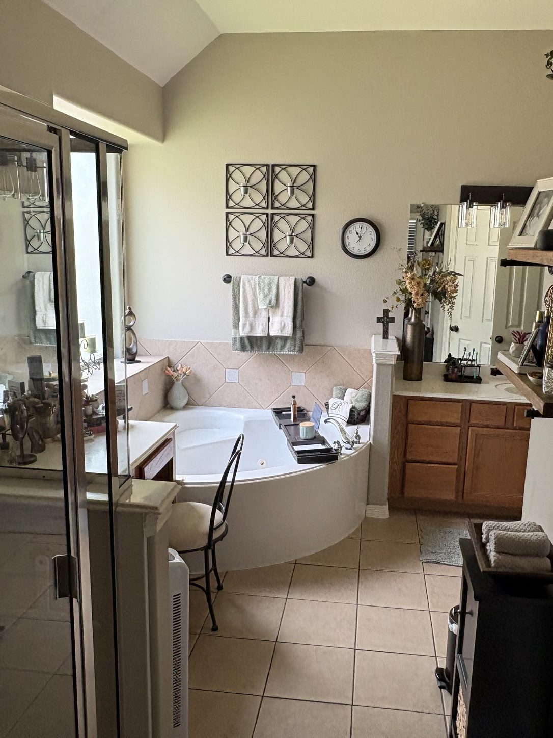 The bathroom before the remodel: a corner tub beneath a window, beige tile and wood-tone vanity cabinetry