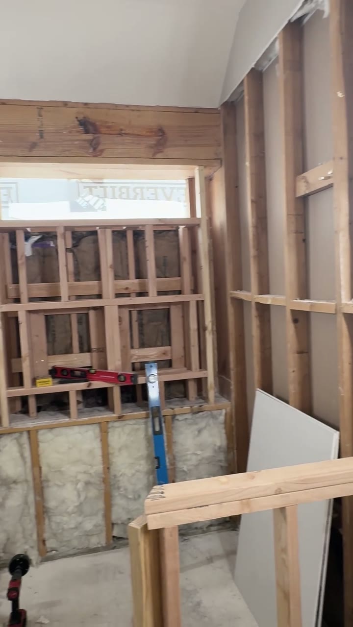 The shower corner mid-build: the window wall opened to the studs and new knee walls framed