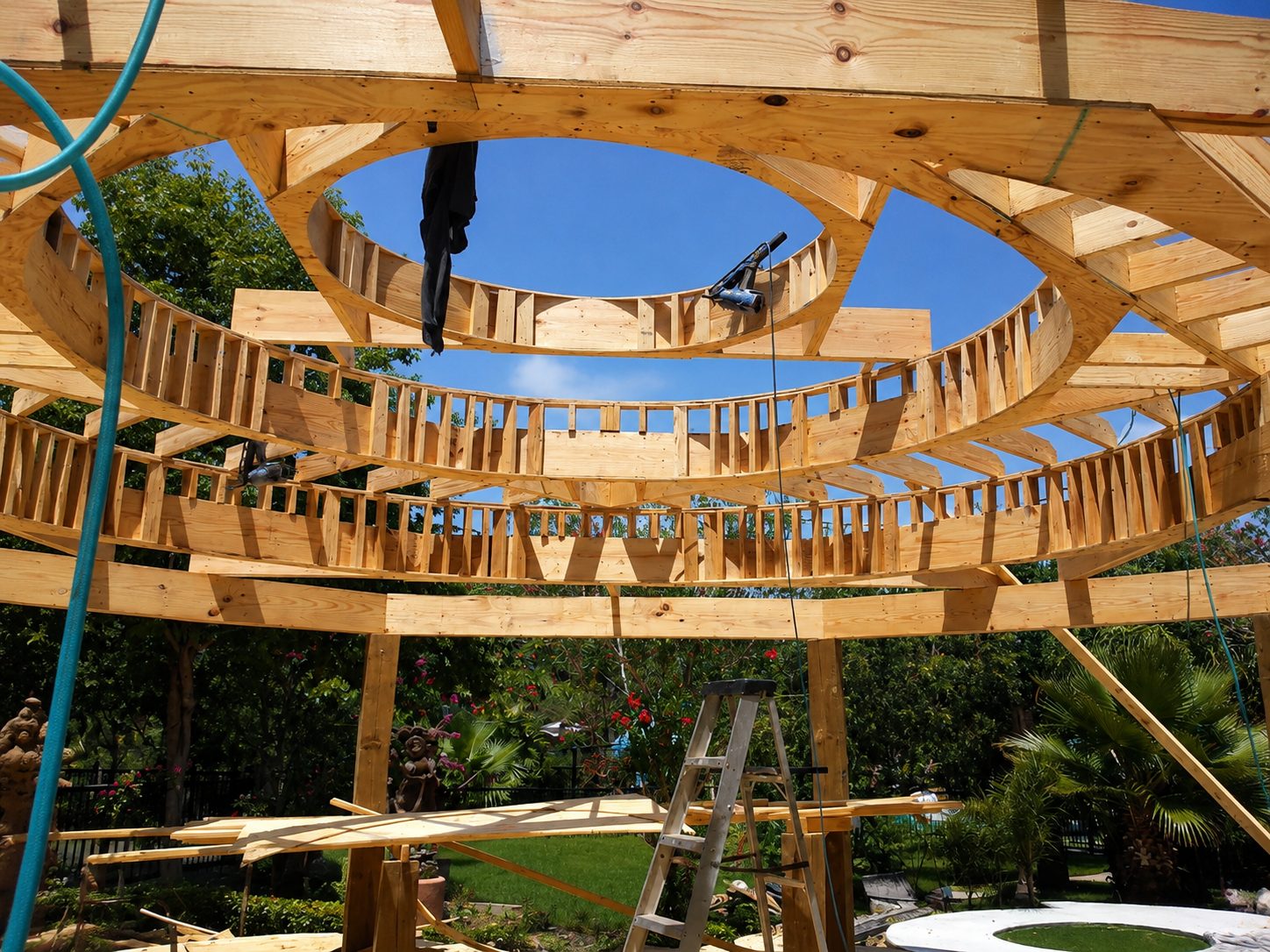 The gazebo under construction: hand-cut timber rafters forming an open dome against a clear blue sky